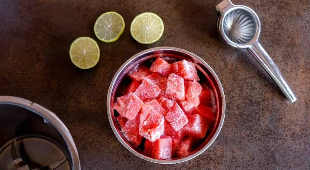 Hand scooping fresh watermelon sorbet with a metal ice cream scoop