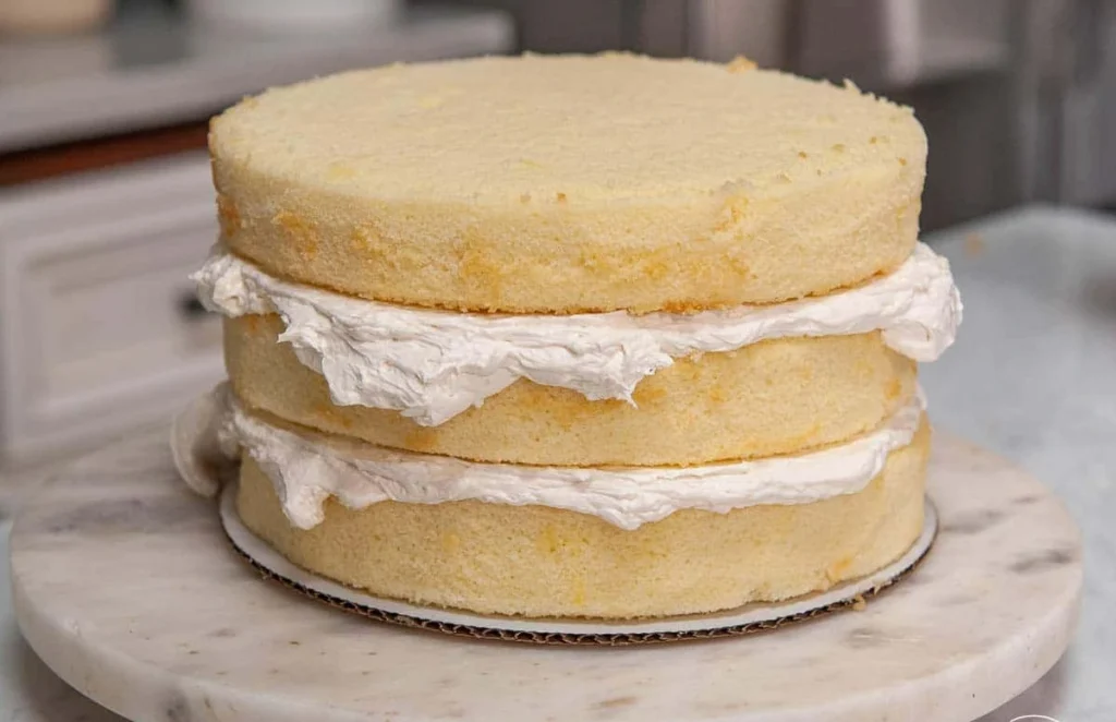 Single slice of fluffy vanilla cake with creamy frosting on a dessert plate