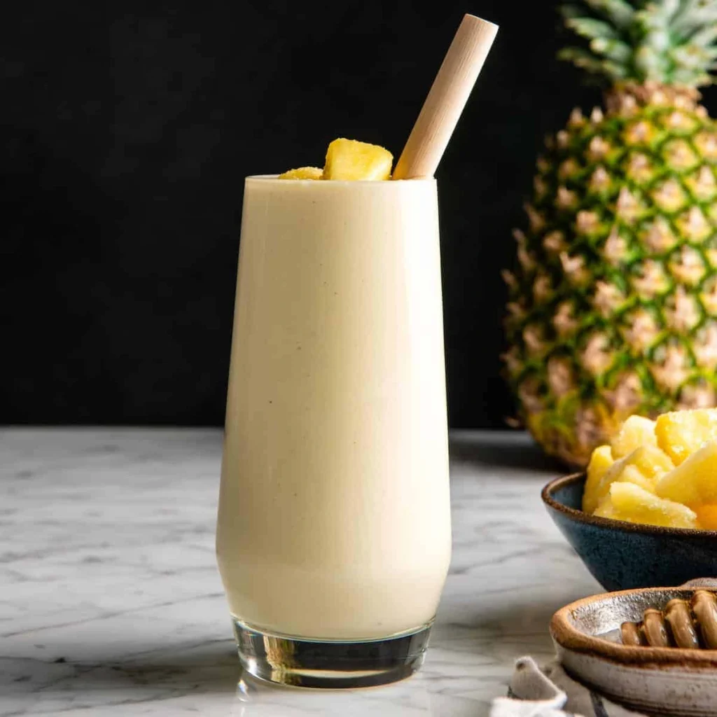 Fresh pineapple chunks, banana, and coconut milk arranged on a kitchen counter before blending.